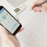 Tangan menggunakan smartphone dengan aplikasi kalender untuk mengatur jadwal kerja